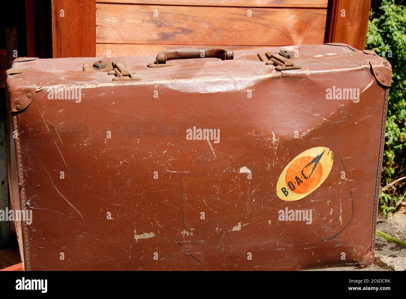 Eine alte, zerschlagene Suicase, die seit einiger Zeit in einem Nebengebäude gelagert wird und auf der noch ein B.O.A.C. Gepäcketikett aus den 1950er Jahren steht Stockfoto
