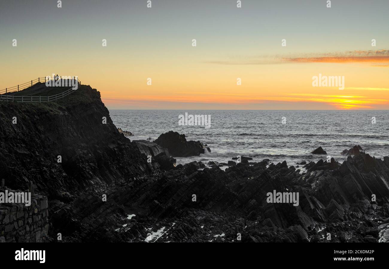Paar beobachten den Sonnenuntergang vom Hartland Quay - Hartland, Devon, Großbritannien Stockfoto