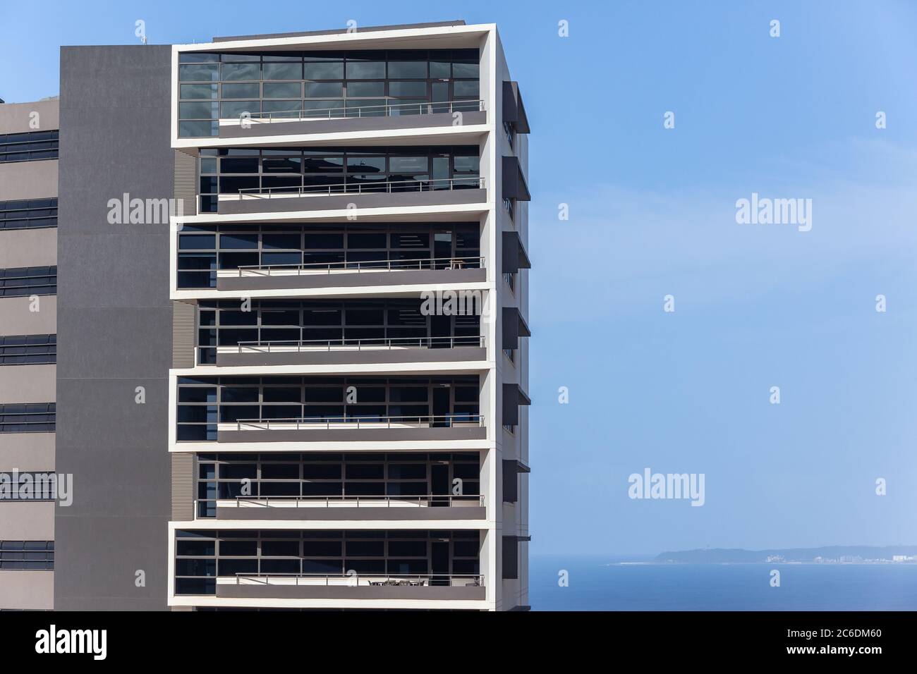 Neues modernes Bürogebäude mit Blick auf blauen Himmel und Meer Wasser Foto Abschnitt der Etagen mit Balkon Veranden. Stockfoto