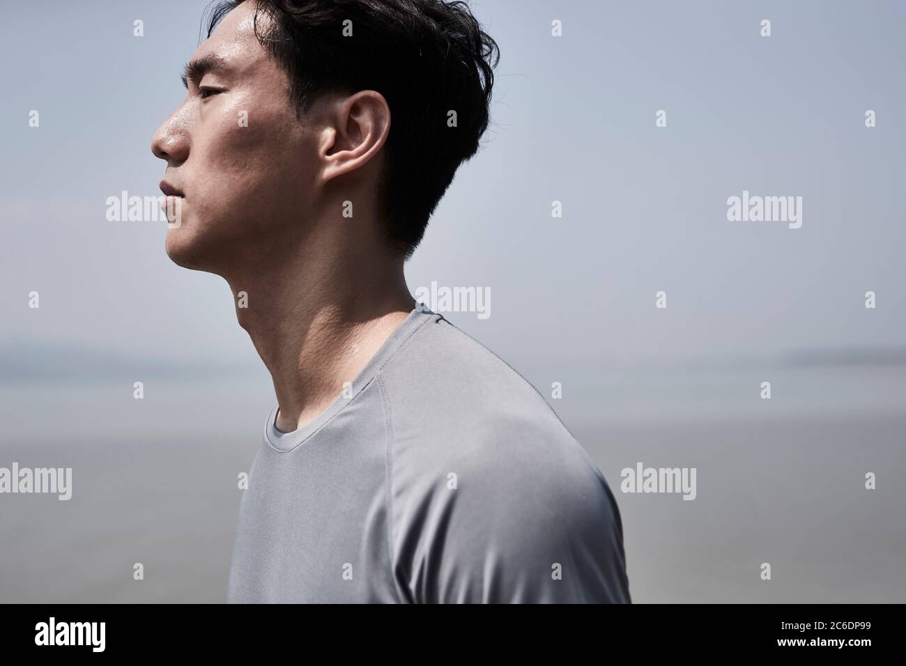 Außenportrait eines jungen asiatischen Mannes, der am Meer steht, Seitenansicht Stockfoto