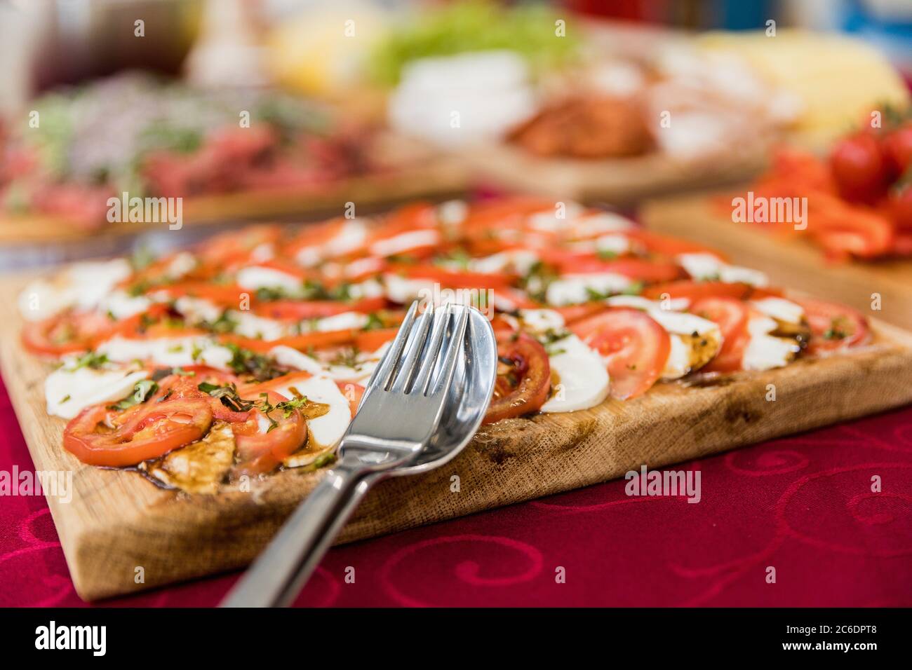 Frische Mozzarella und Salat auf einem Holztablett. Nahaufnahme auf einem Löffel und einer Gabel. Stockfoto