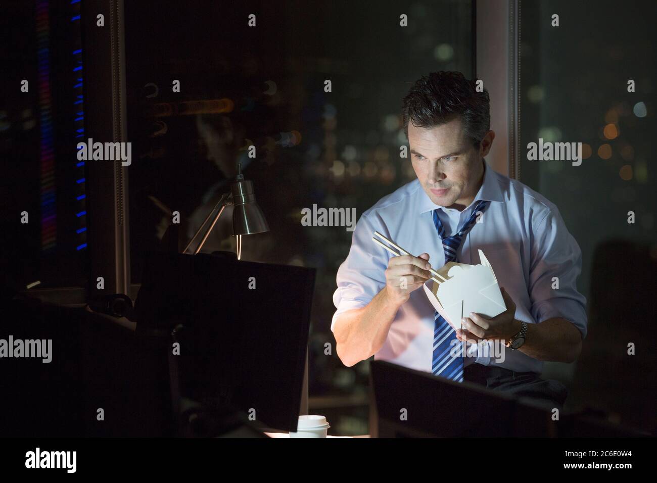 Geschäftsmann, der abends Essen zum Mitnehmen im Büro isst Stockfoto