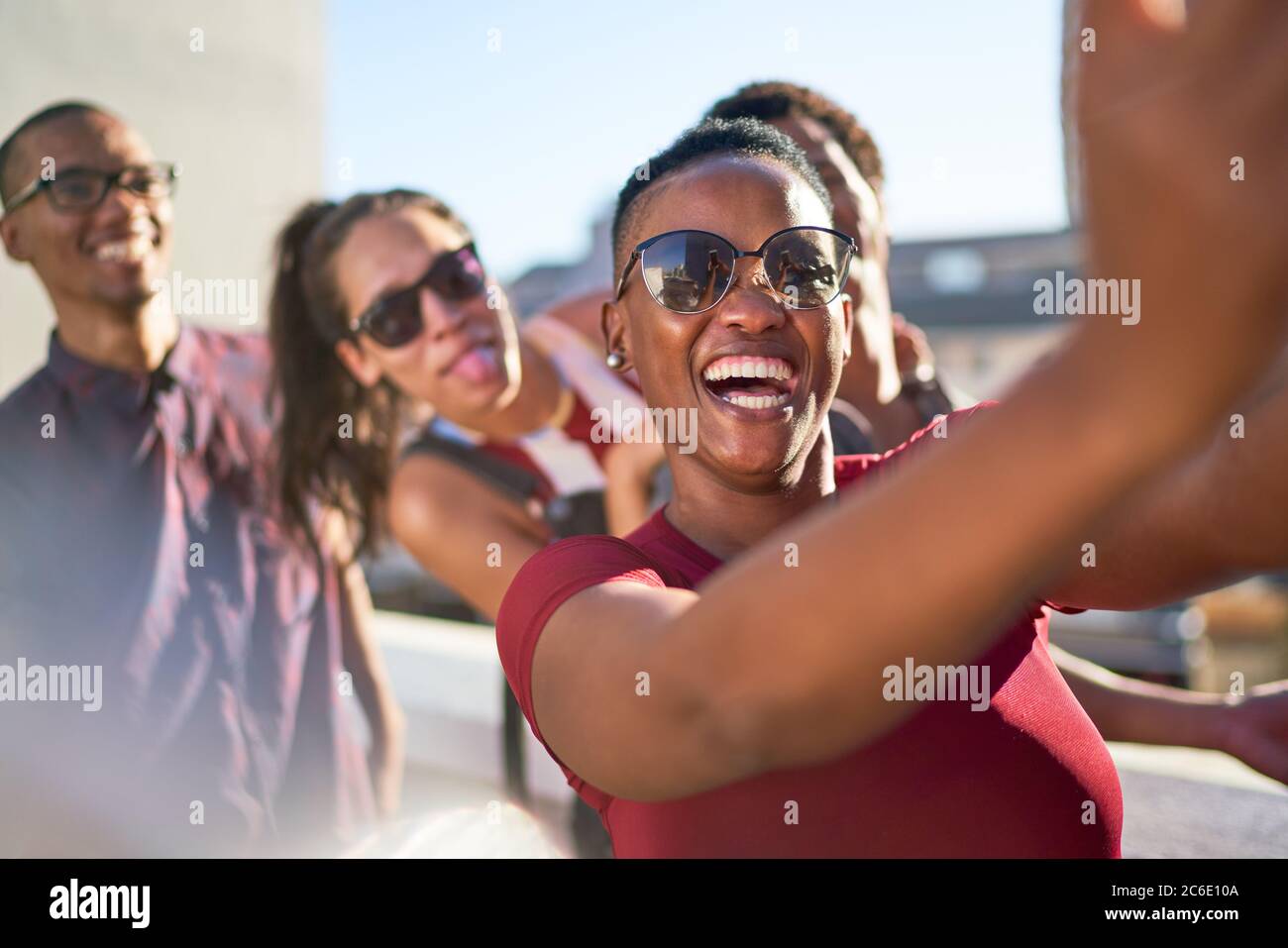 Fröhliche verspielte junge Freunde, die Selfie auf der sonnigen Terrasse machen Stockfoto