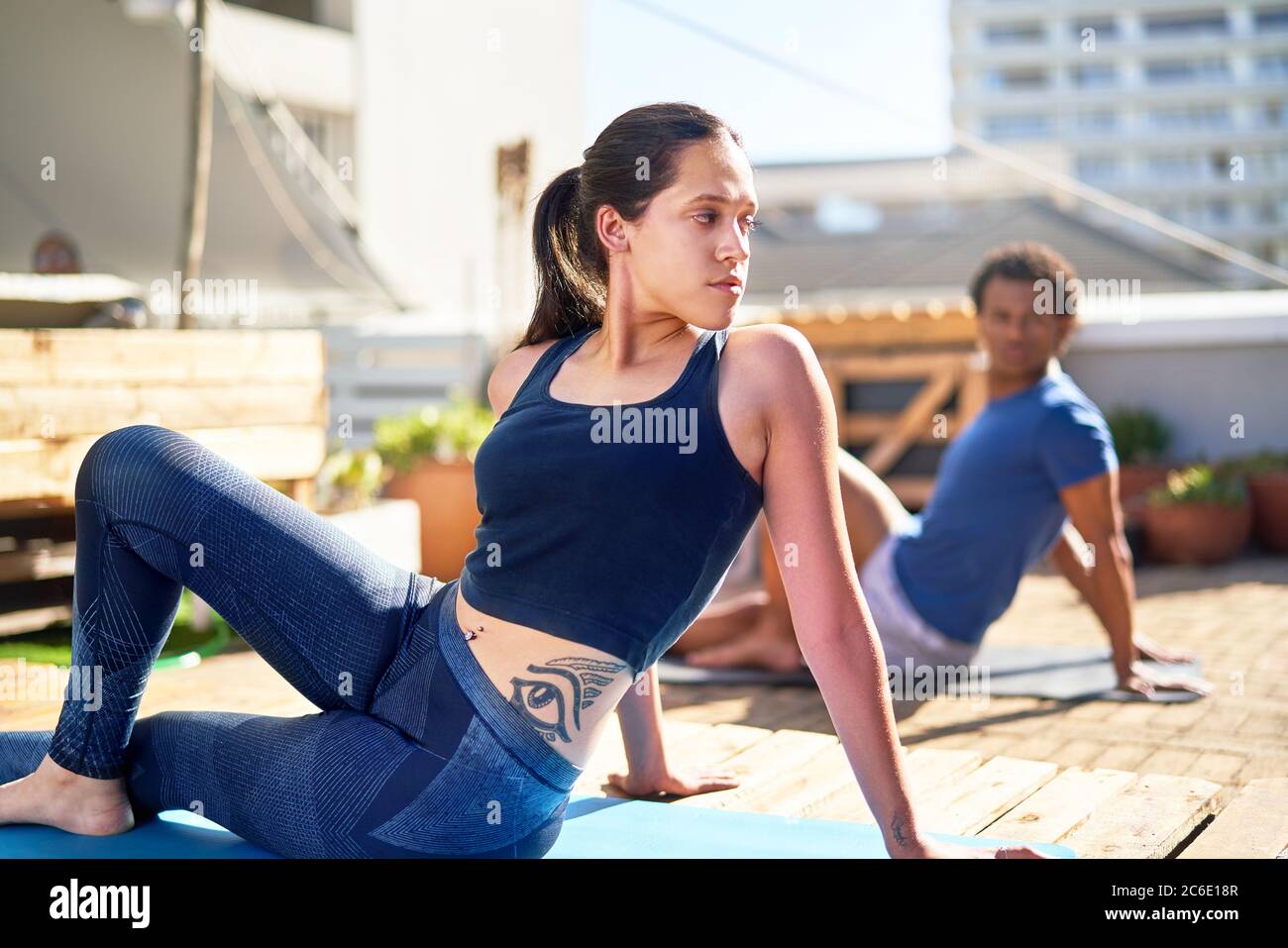 Junge Frau praktiziert Yoga auf sonnigem Dach Stockfoto