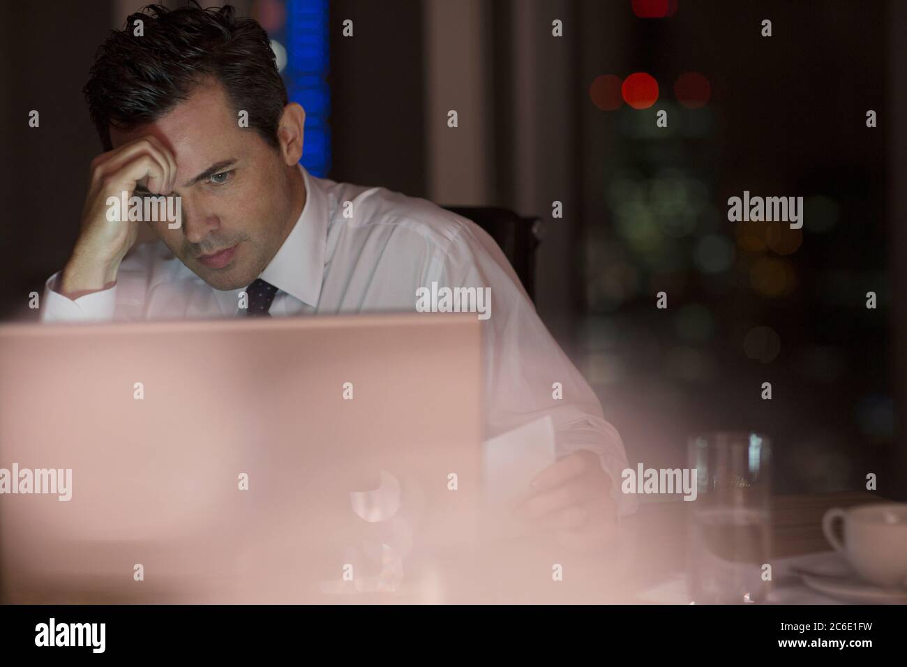 Gestresster Geschäftsmann arbeitet spät am Laptop im Büro Stockfoto