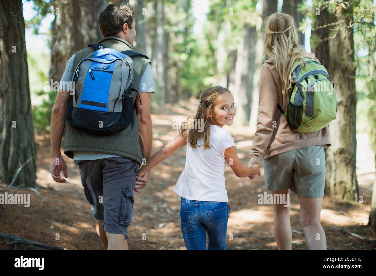 Lächelndes Mädchen wandern mit Eltern in Wäldern Stockfoto