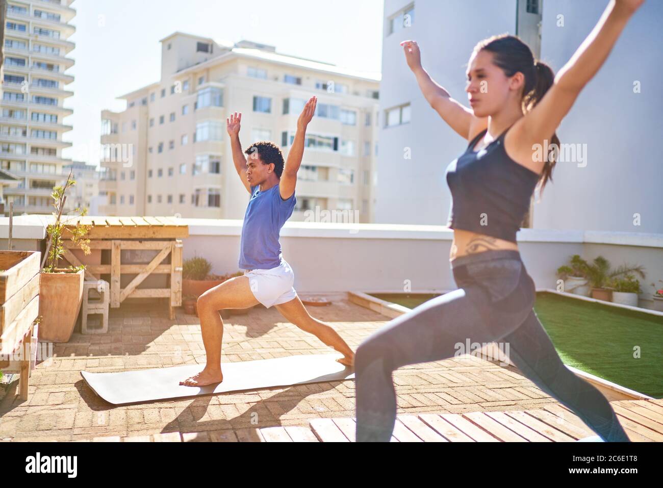 Junges Paar, das Yoga auf dem sonnigen städtischen Dachbalkon praktiziert Stockfoto