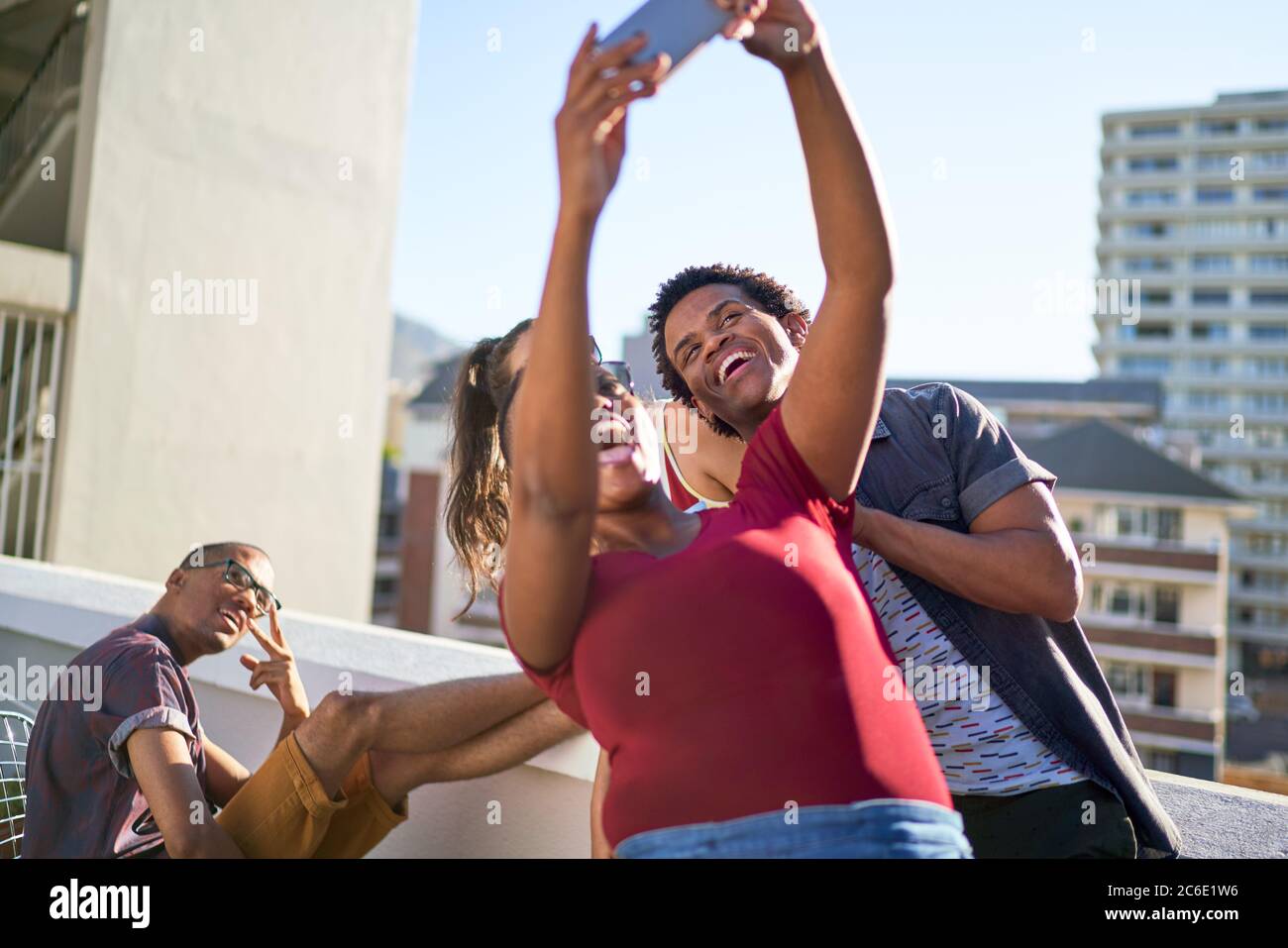 Glückliche junge Freunde, die Selfie auf dem sonnigen städtischen Dach machen Stockfoto