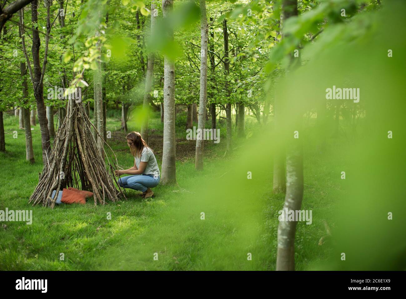 Frau, die im Wald Ast-Tipi macht Stockfoto