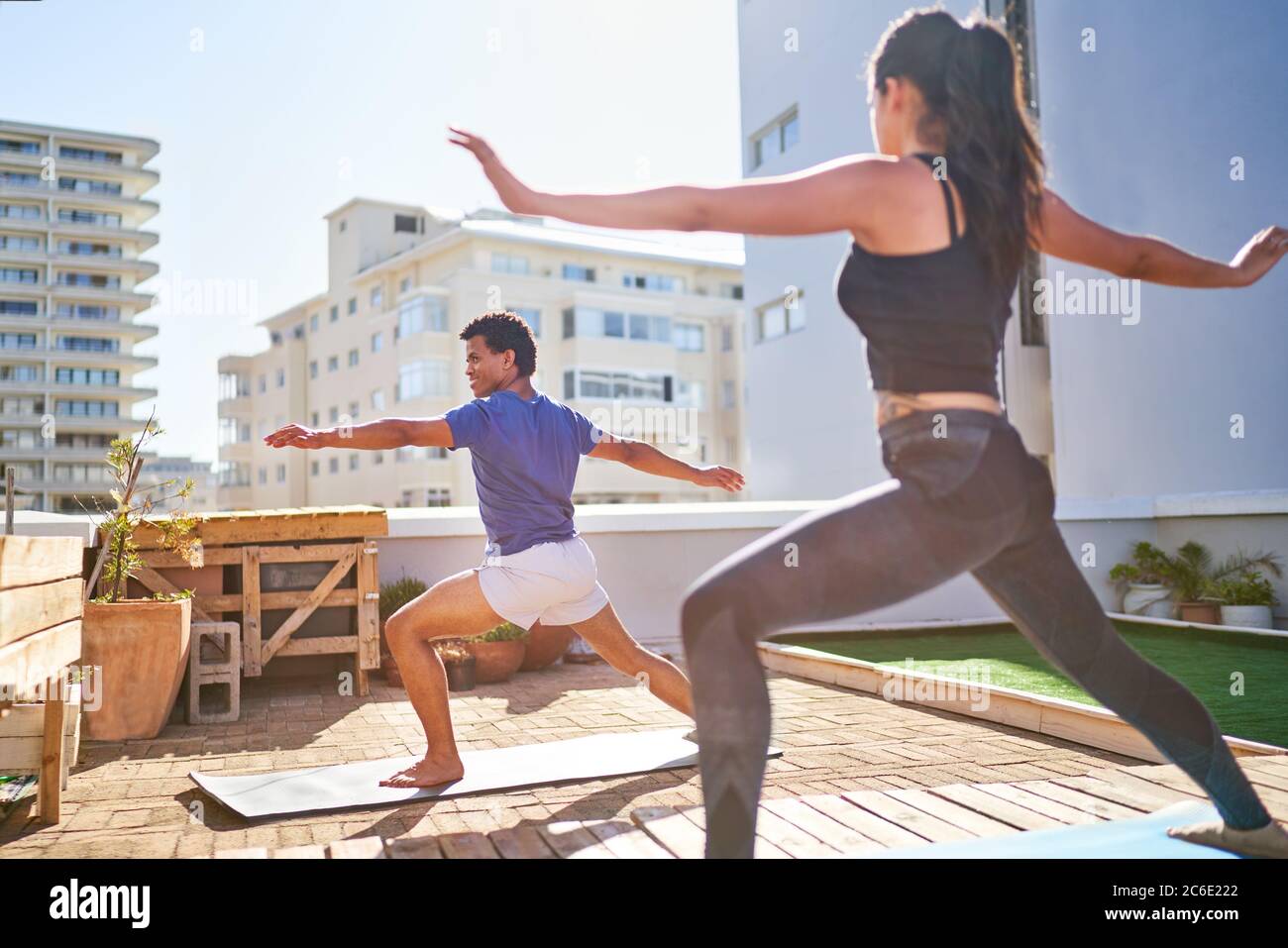 Junges Paar, das Yoga auf dem sonnigen städtischen Balkon praktiziert Stockfoto