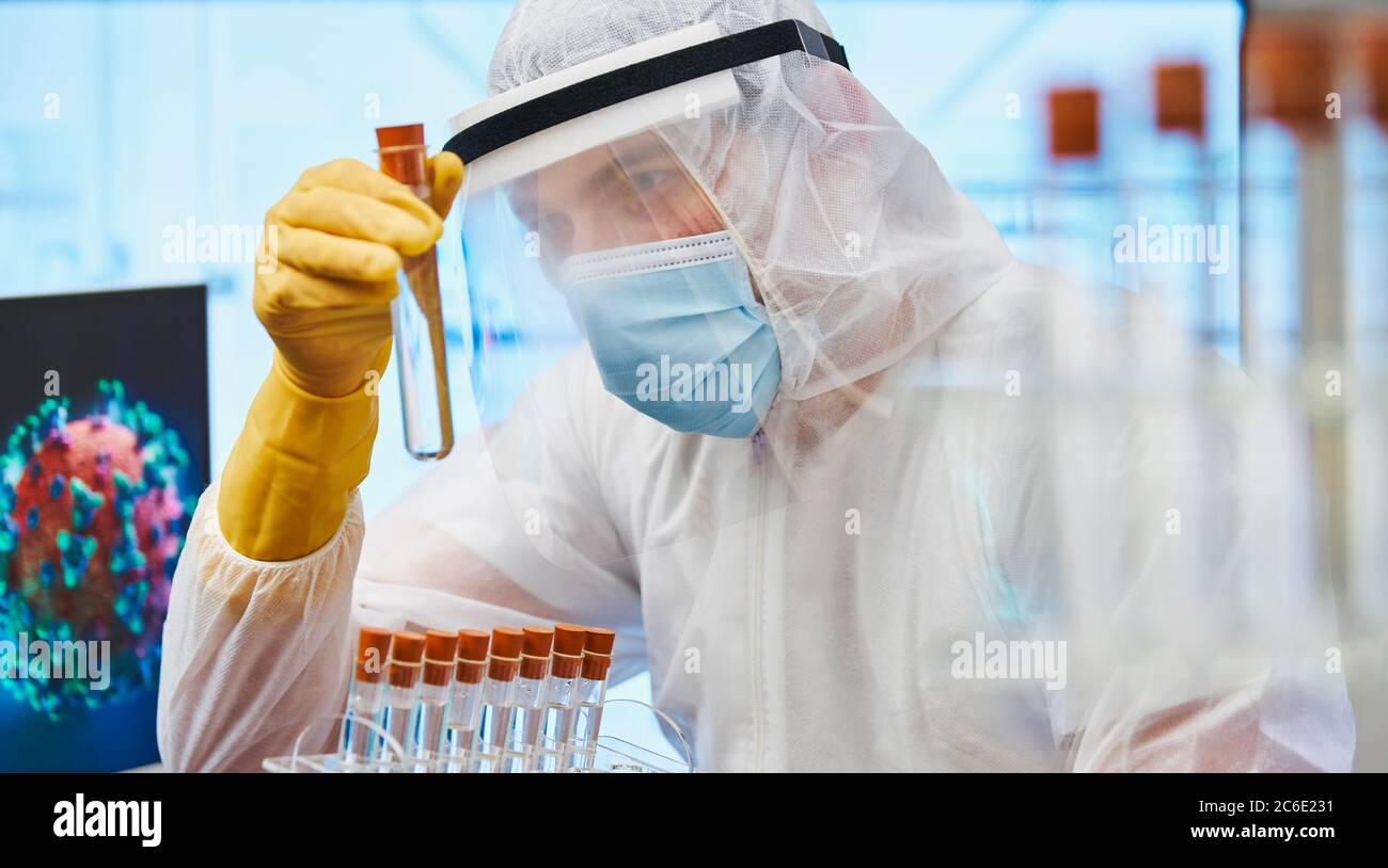 Fokussierter männlicher Wissenschaftler mit Reagenzglas, der Coronavirus erforscht Stockfoto