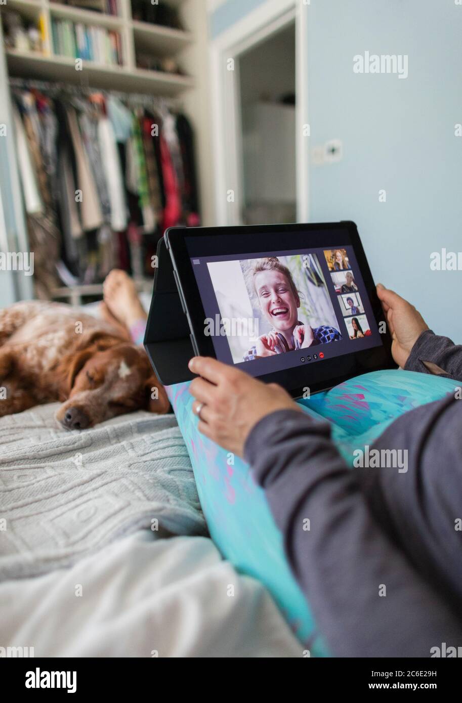Frau mit digitalen Tablet-Video chatten mit Freunden auf dem Bett mit Hund Stockfoto