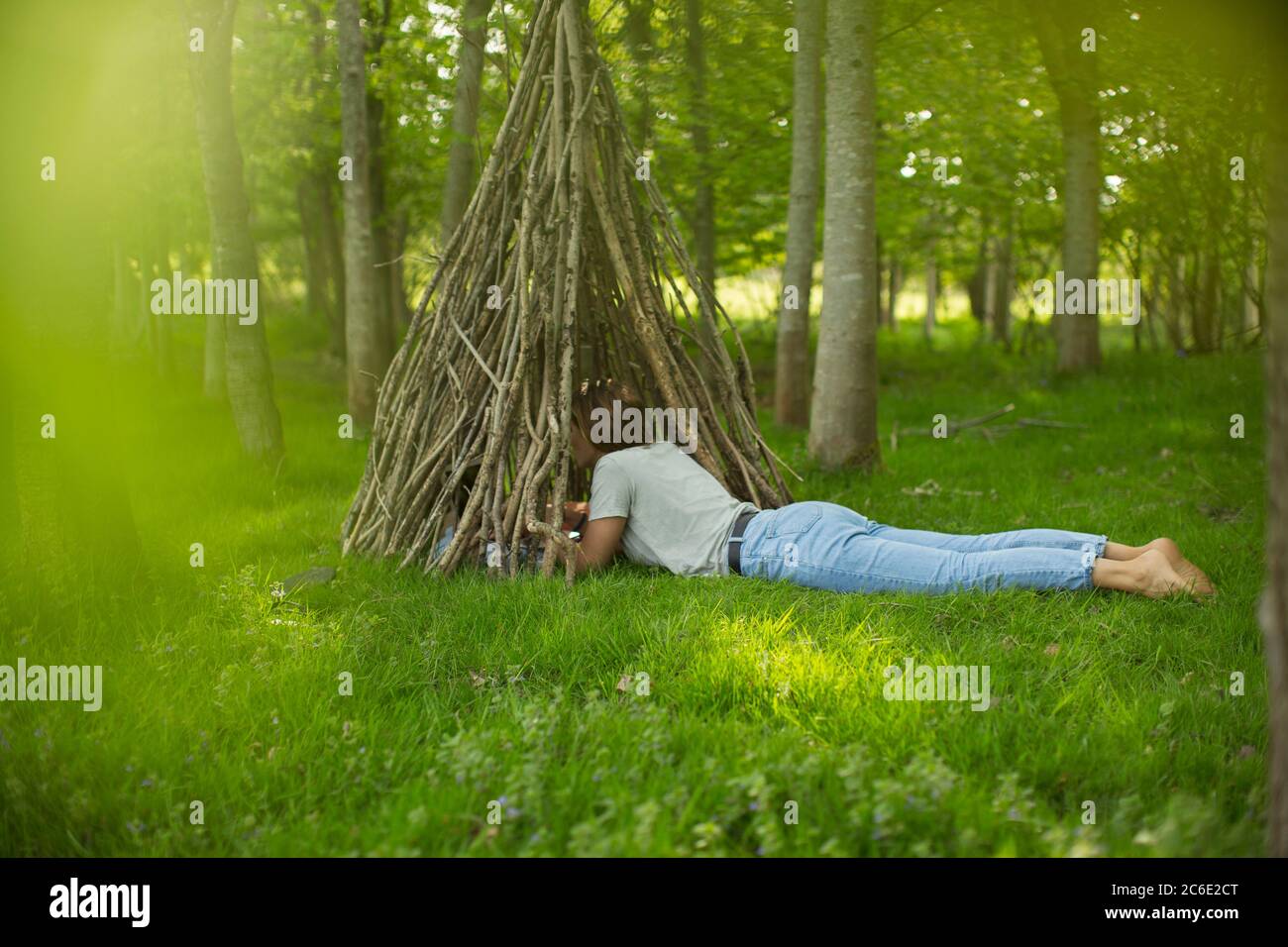 Frau liegt an Ast Tipi im Wald Stockfoto