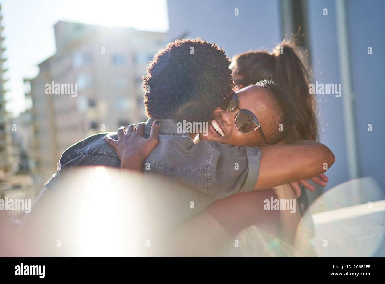 Glückliches junges Paar umarmt auf sonnigen städtischen Balkon Stockfoto