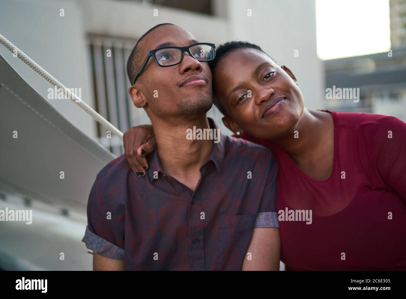 Portrait selbstbewusst liebevoll junges Paar umarmt auf der Terrasse Stockfoto