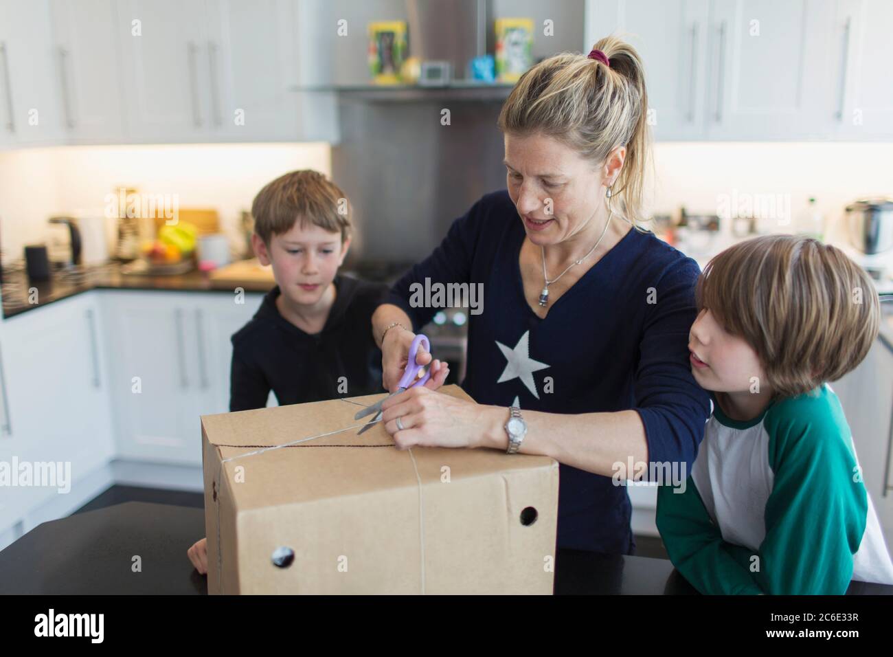 Mutter und Söhne öffnen Paket in der Küche Stockfoto