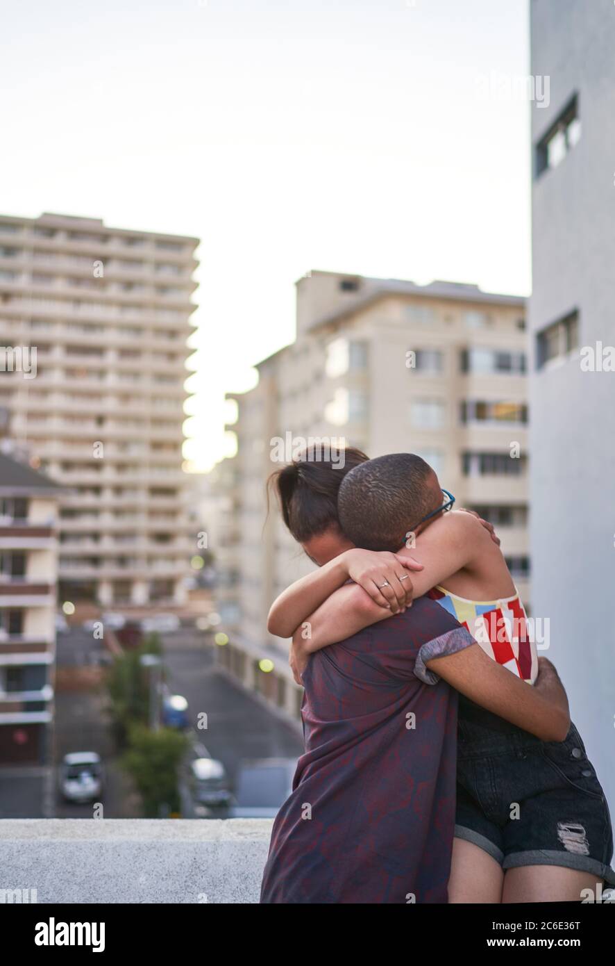 Glückliches junges Paar umarmt auf städtischen Balkon Stockfoto