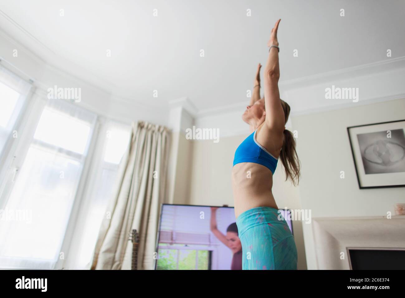 Frau Yoga online im Wohnzimmer üben Stockfoto