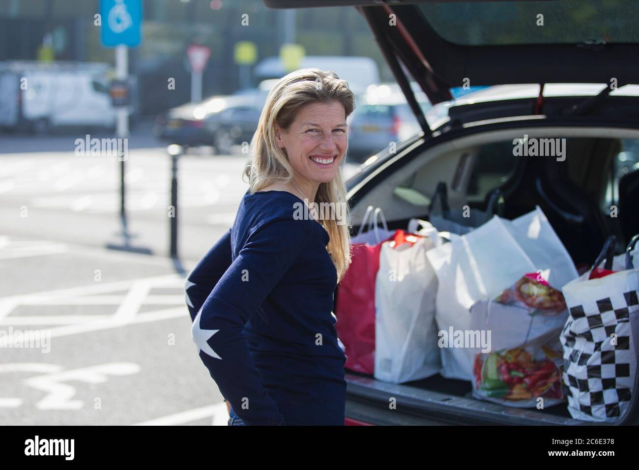 Portrait glückliche Frau mit Lebensmittelbeutel an der Tasche des Autos Stockfoto