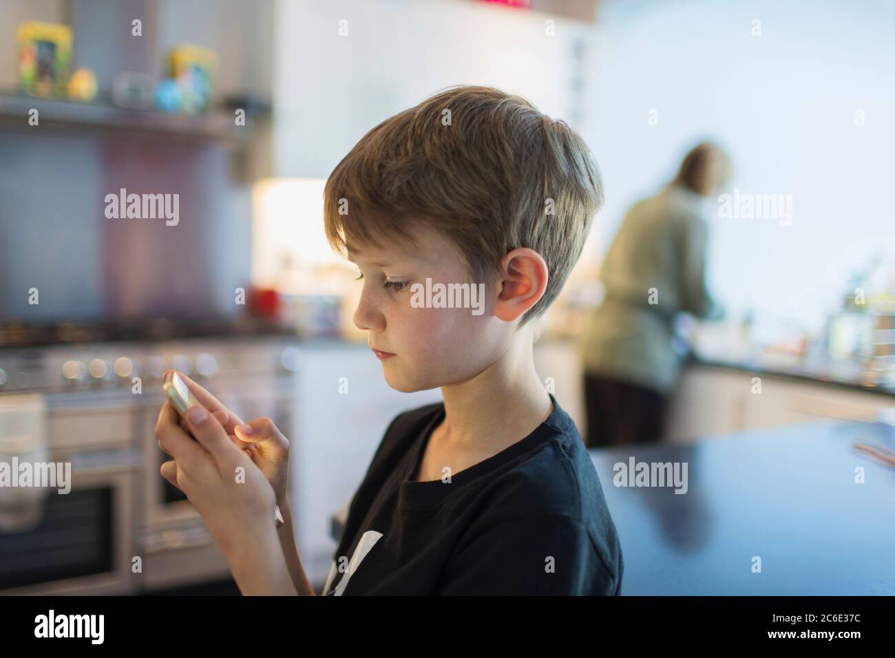 Junge mit Smartphone in der Küche Stockfoto