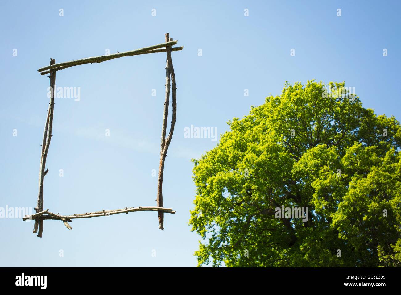 Holzstab Bilderrahmen gegen sonnigen blauen Himmel mit Baum Stockfoto