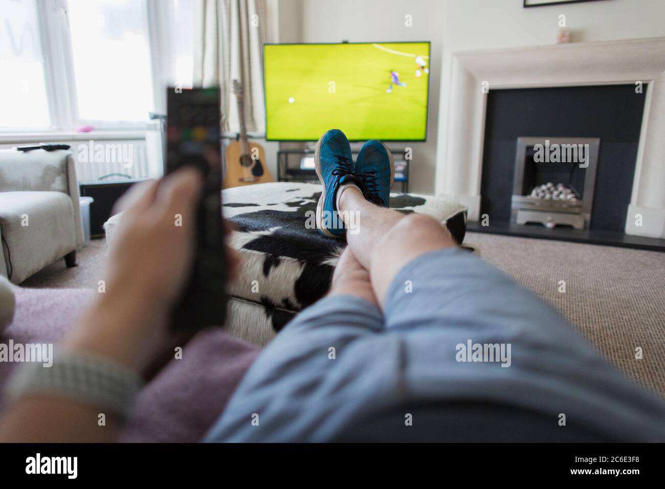 POV Mann auf dem Sofa mit Fernbedienung beobachten Fußballspiel im Fernsehen Stockfoto