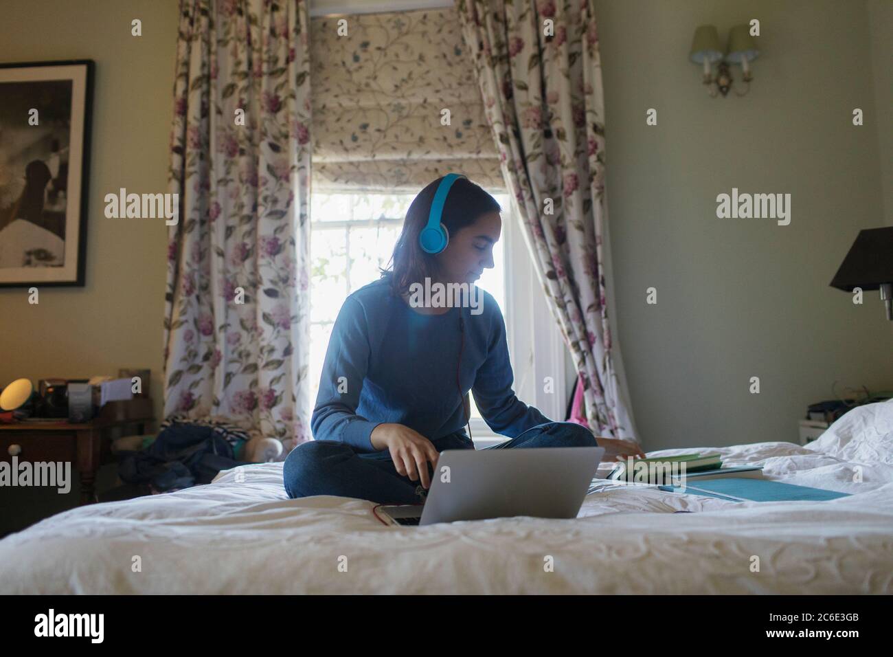 Teenager Mädchen mit Kopfhörer und Laptop Lernen auf dem Bett Stockfoto