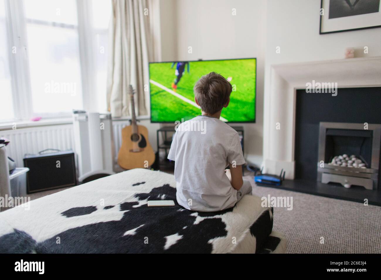 Junge, der Fußballspiel im Wohnzimmer am Fernseher ansieht Stockfoto