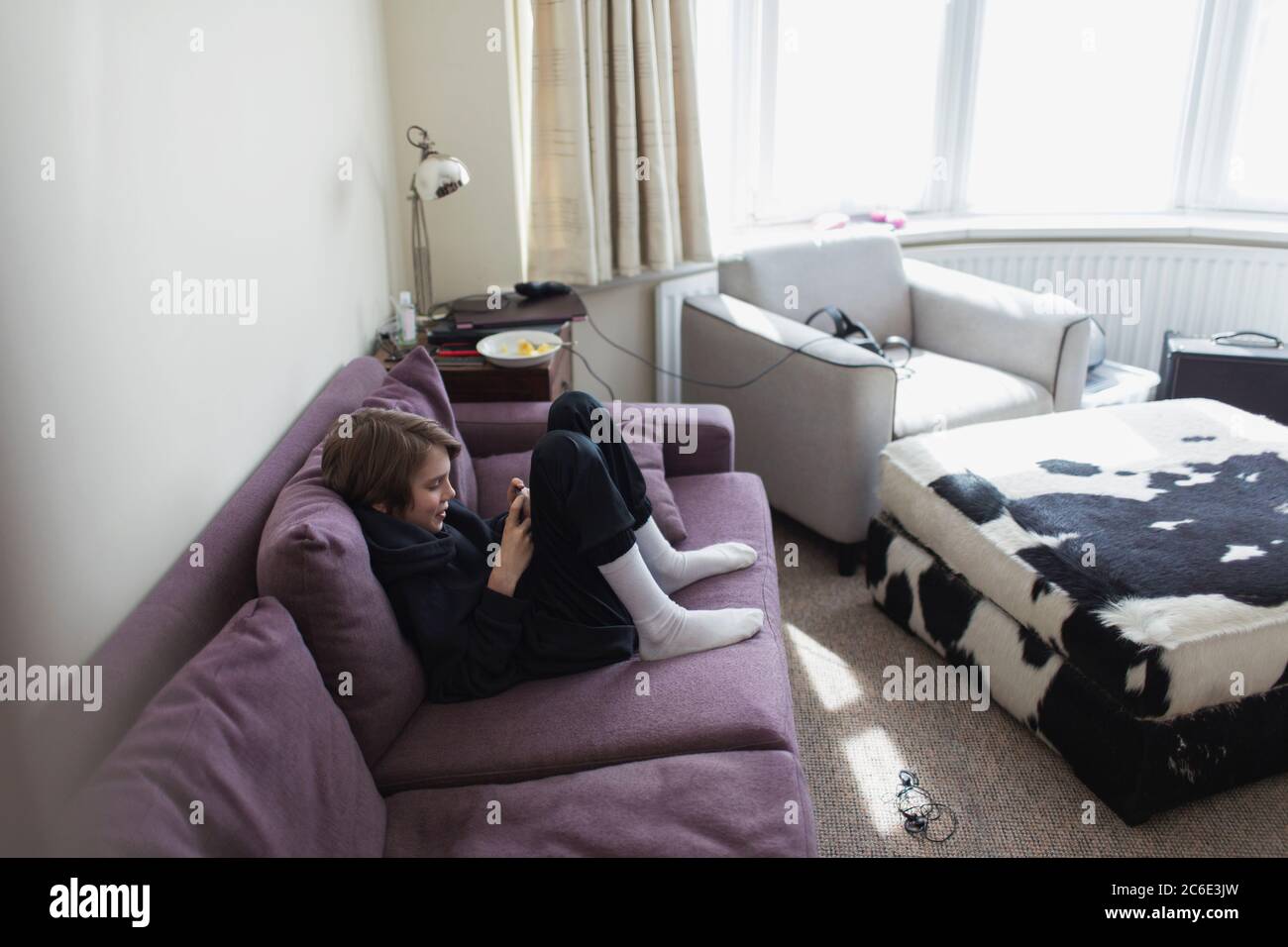 Junge mit Smartphone auf Wohnzimmer Sofa Stockfoto