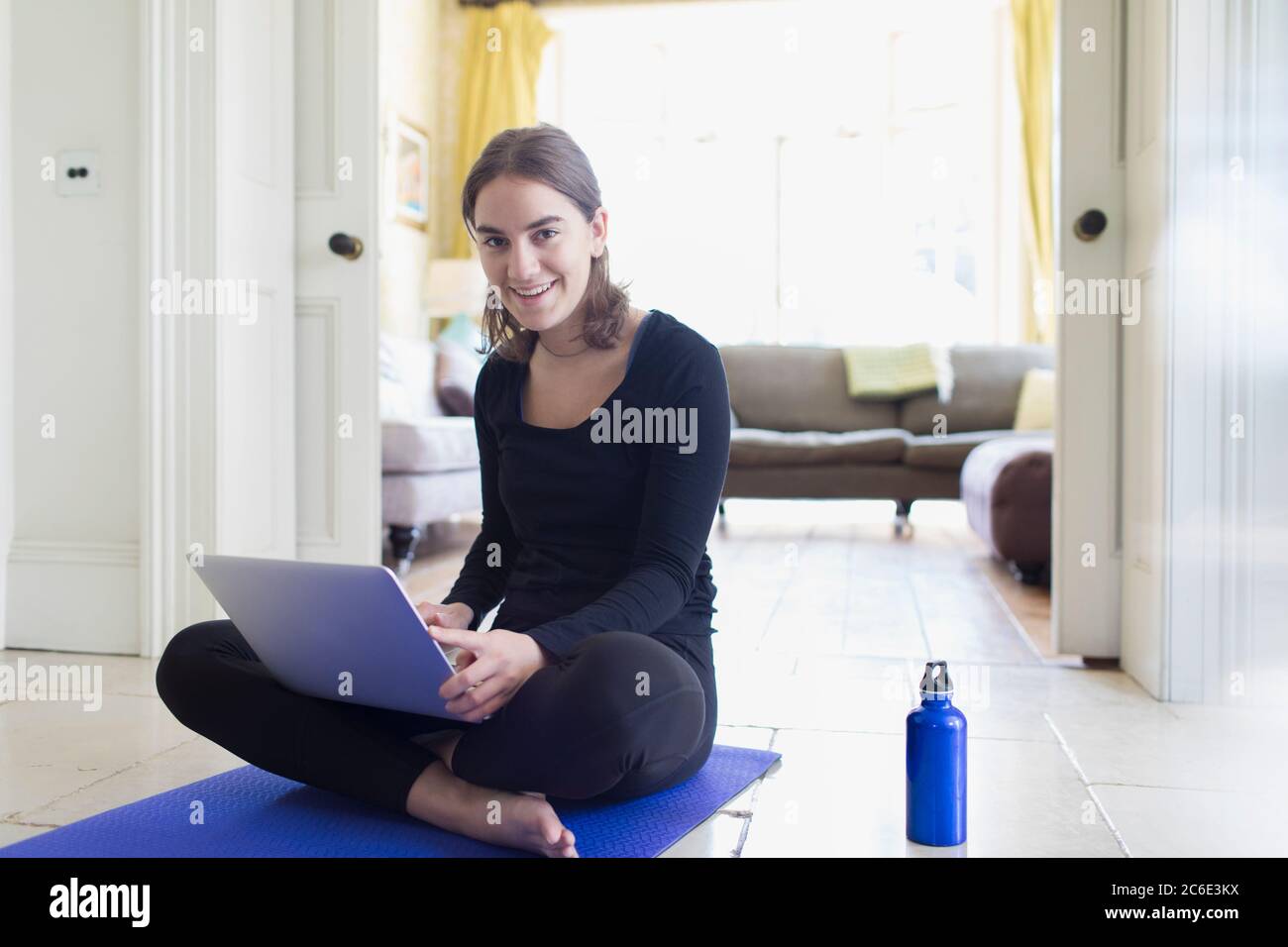 Portrait lächelndes Teenager-Mädchen, das zu Hause mit Laptop Online Yoga praktiziert Stockfoto