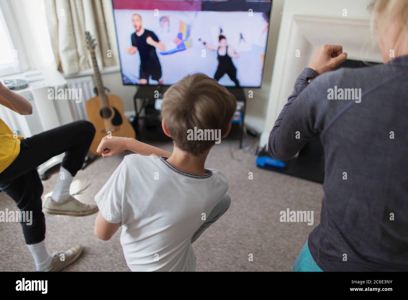 Mutter und Söhne trainieren online im Wohnzimmer beim Fernsehen Stockfoto