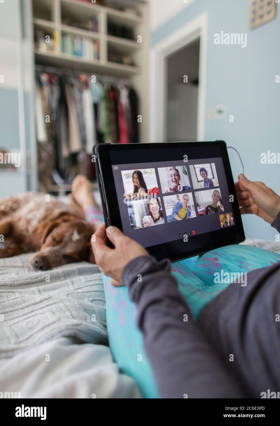 Frau mit digitalen Tablet-Video chatten mit Freunden auf dem Bett mit Hund Stockfoto