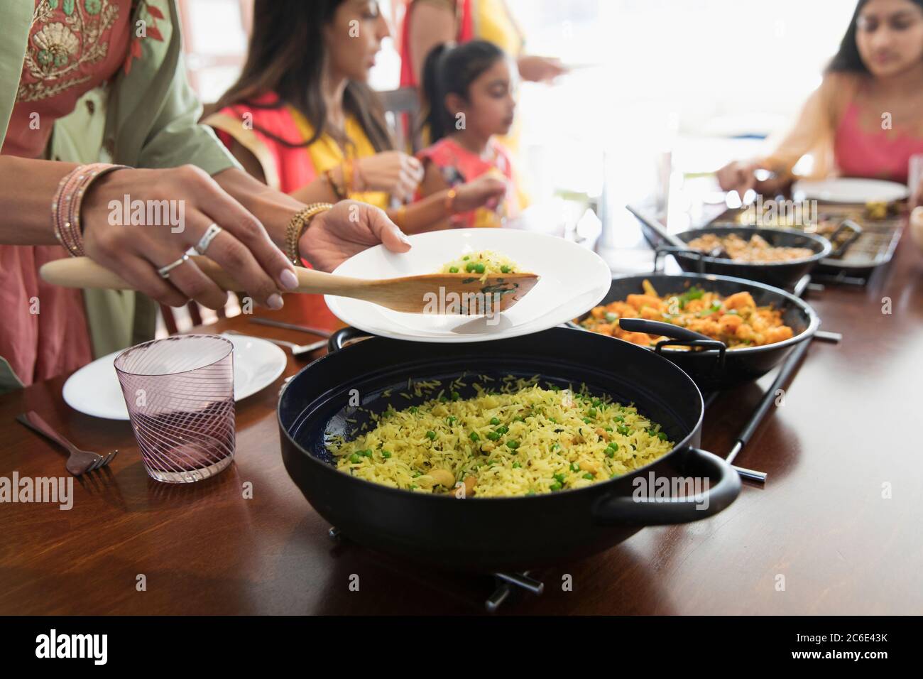 Indische Frauen in Saris servieren und essen Essen am Tisch Stockfoto