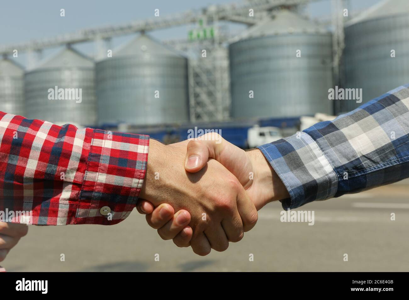 Geschäftsleute schütteln die Hände gegen Silos. Agrarwirtschaft Stockfoto