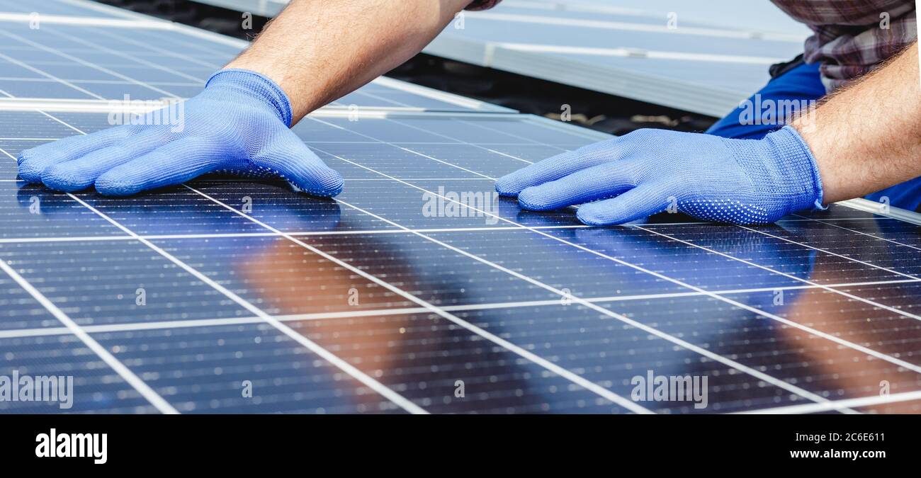Männliche Arbeiter Hände in leuchtet auf Solarpanel, Techniker Installation von Solarpaneelen auf dem Dach. Alternative Energie Sonnenenergie Energie, ökologisches Konzept. Lang Stockfoto