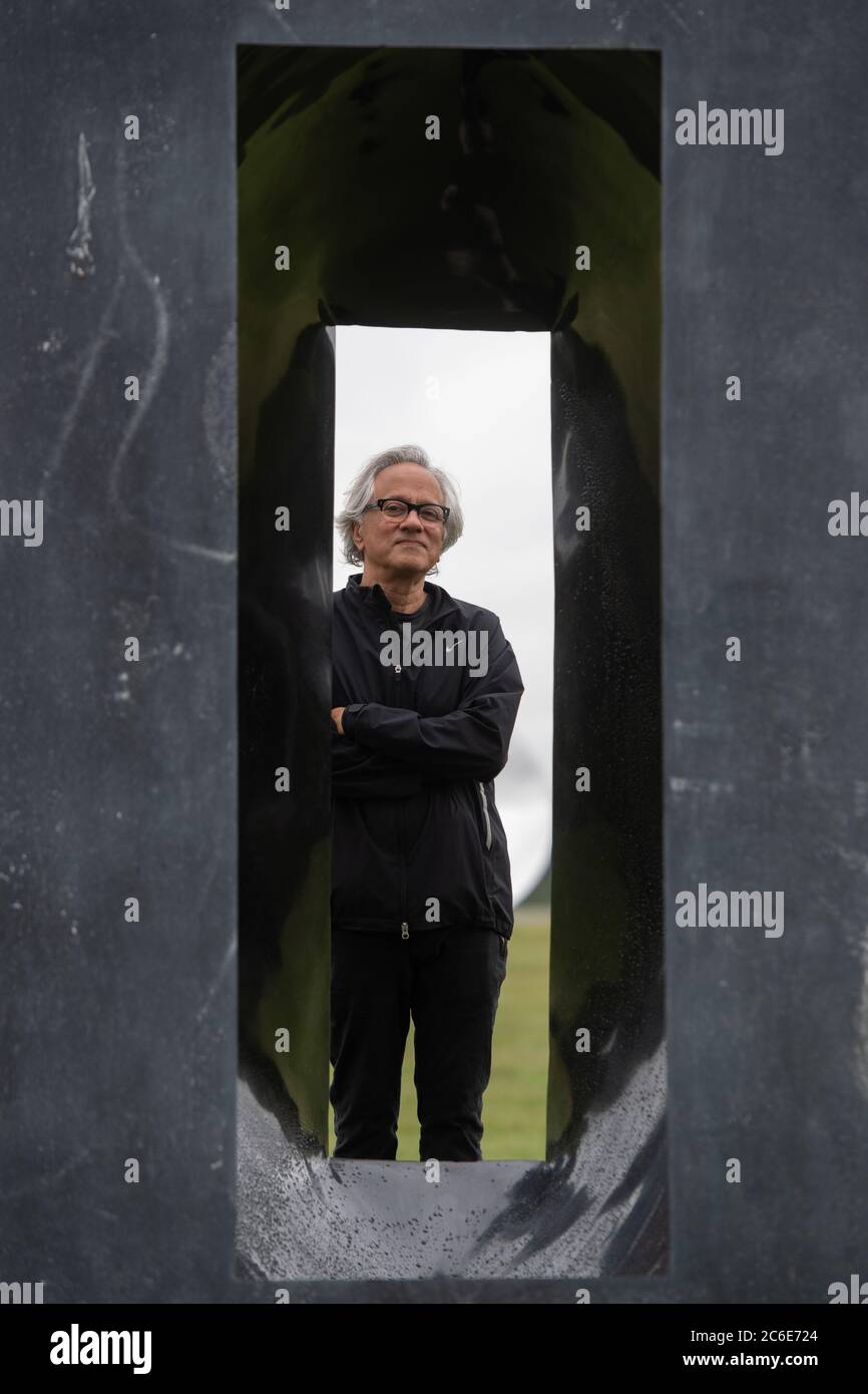 Der Künstler Anish Kapoor blickt vor der Eröffnung seiner größten britischen Ausstellung von Outdoor-Skulpturen in der Houghton Hall, King's Lynn, durch eine seiner Skulpturen. Stockfoto