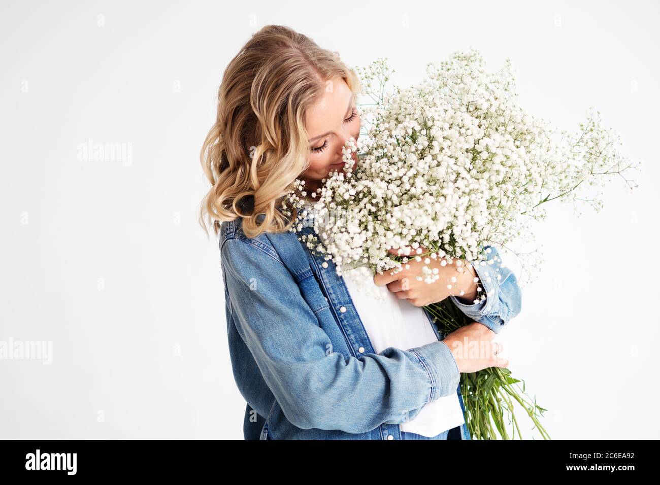 Stilvolle junge blonde Frau mit einem Bouquet von Gypsophila. Porträt auf weißem Hintergrund. Happy Girl mit einem Blumenstrauß, Blumenlieferung. Stockfoto