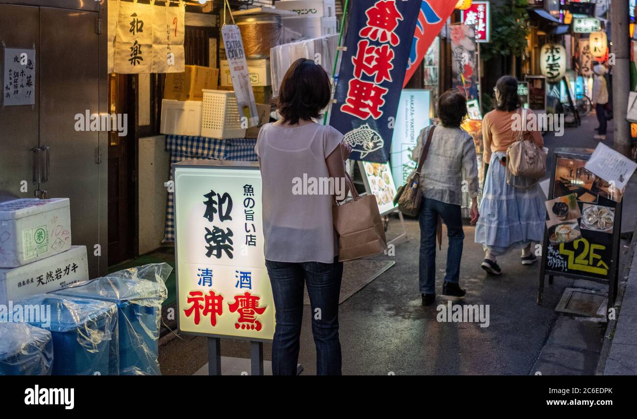 Menschen, die in der Hintergasse von Shimbashi spazieren, ein beliebtes Ziel für Büroangestellte in Tokio, Japan bei Nacht. Stockfoto