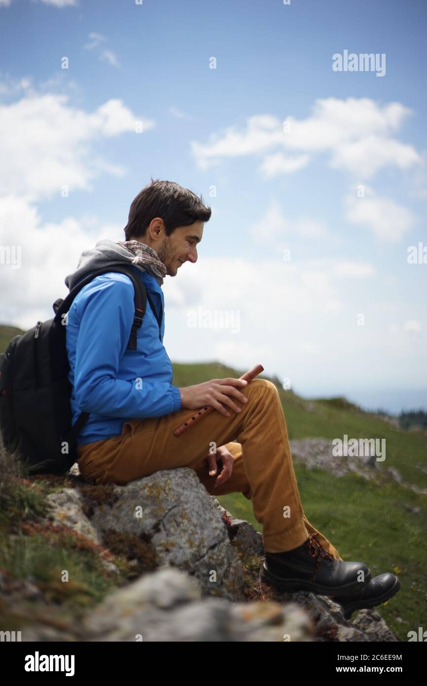 Ein junger männlicher Tourist auf dem Gipfel des Stara Planina (Balkan) und genießen die Aussicht. In einer Hand hält er eine hölzerne Rohrleitung. Stockfoto