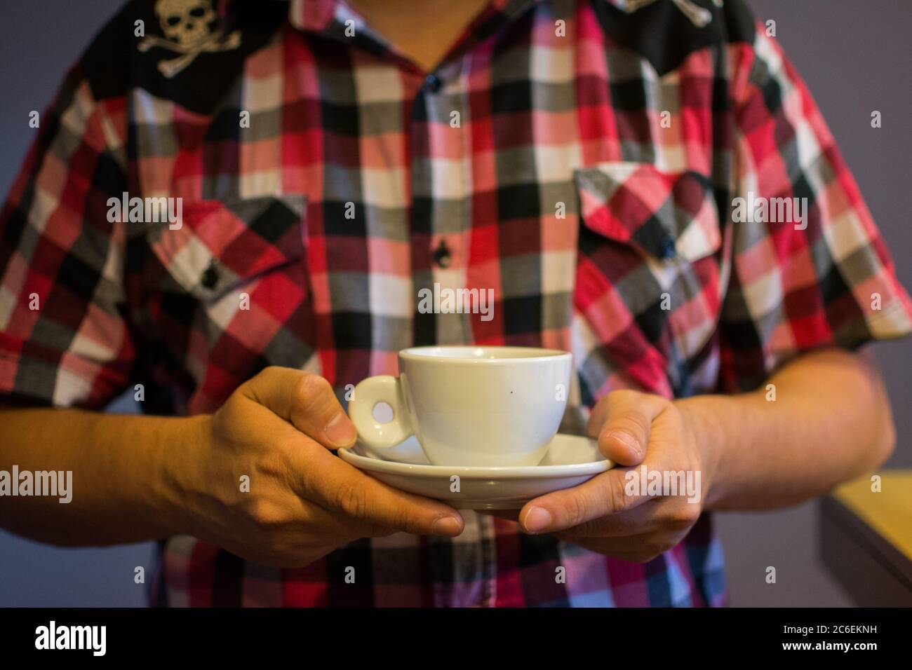 Mann im karierten Hemd hält eine Tasse Kaffee Stockfoto