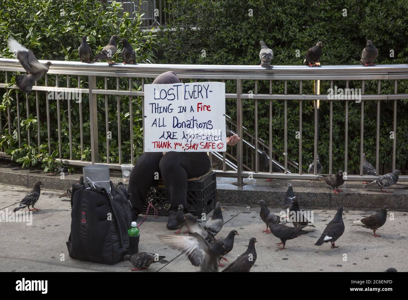 Frau, die alles in einem Feuer verloren hat, sagt sie, bittet um Hilfe, am Columbus Circle am Central Park in New York City zu sitzen. Stockfoto