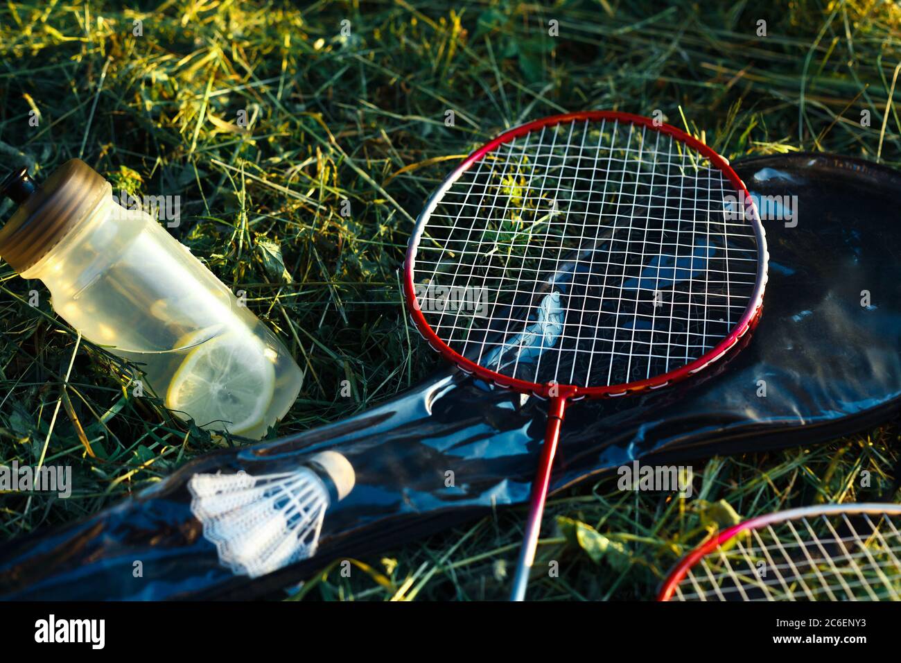 Flasche mit Wasser und Zitronen und Badminton-Schläger in der Gras Nahaufnahme Stockfoto