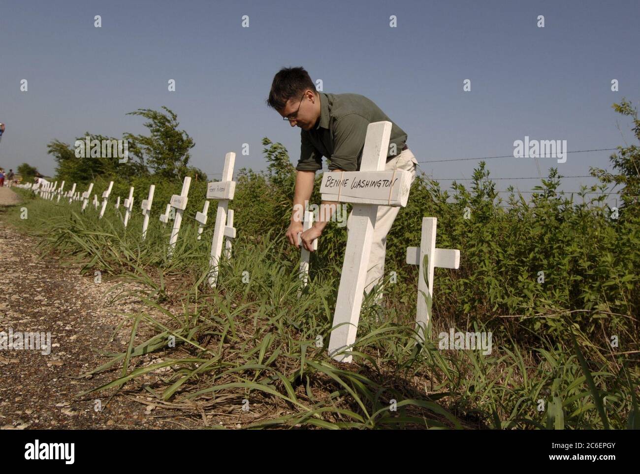Crawford, Texas, USA, 11. August 2005: Ein Antikriegsprotestierender platziert Kreuze, die Soldaten darstellen, die im Irak gestorben sind, entlang der Prairie Chapel Road, in der Nähe von Präsident George W. Bushs Urlaubsranch. Die Anti-Kriegs-Aktivistin Cindy Sheehan und ihre Anhänger halten Mahnwachen in der Nähe der Ranch, während Bush dort Urlaub macht. ©Bob Daemmrich Stockfoto