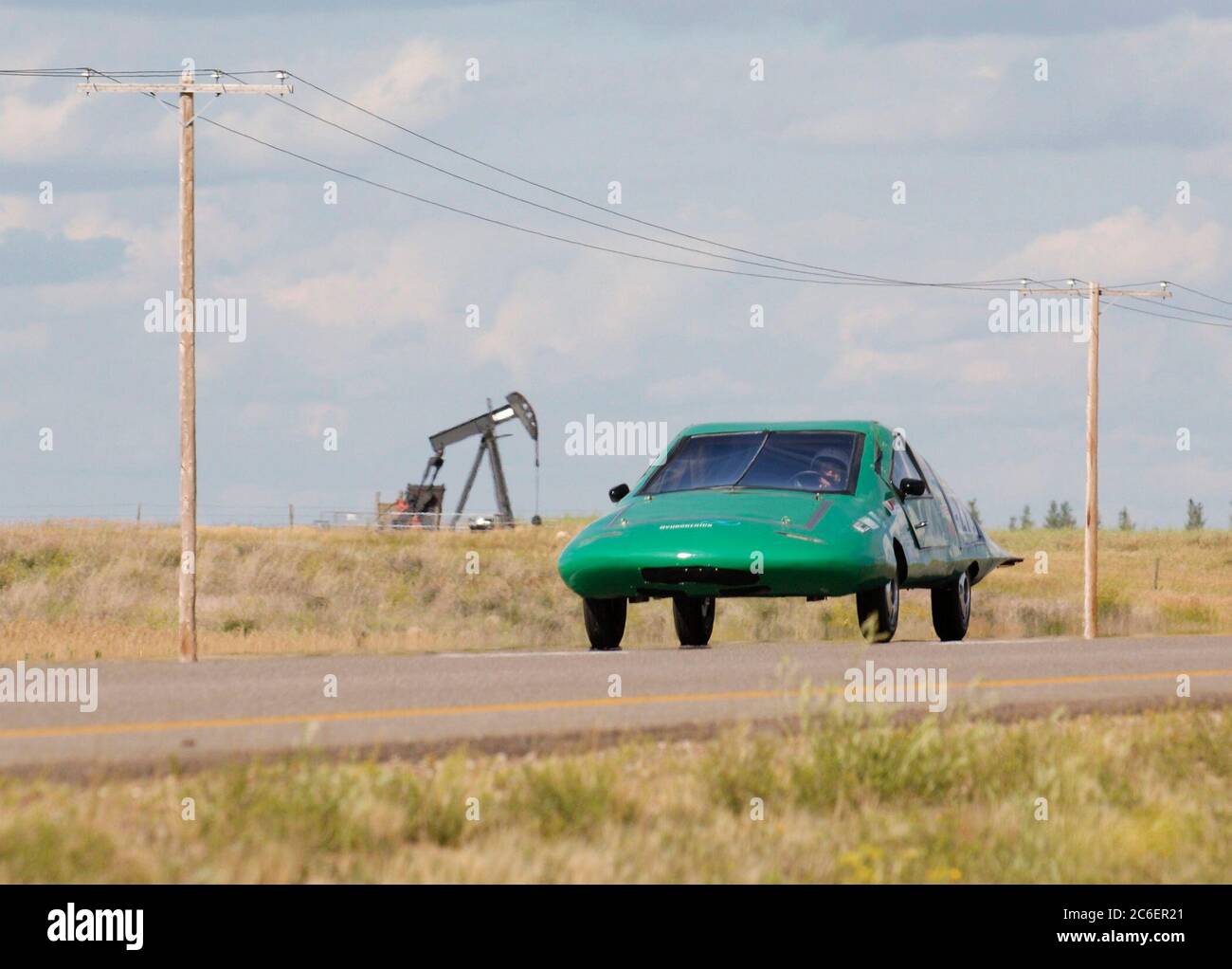 Swift Current, Saskatchewan, Kanada, 25. Juli 2005: Ein mit Wasserstoff betriebenes Fahrzeug der University of North Dakota (USA) fährt auf dem Trans Canada Highway in westlicher Richtung an einem Ölpumpjack vorbei während der North American Solar Challenge, einem 2.500 km langen Solar-Car-Rennen von Austin, Texas, nach Calgary, Alberta, Kanada. Die 10-tägige Veranstaltung umfasst 22 College- und Universitätsteams aus den USA und Kanada. Das Auto ist in einem Vorführkurs im Rennen. ©Bob Daemmrich Stockfoto