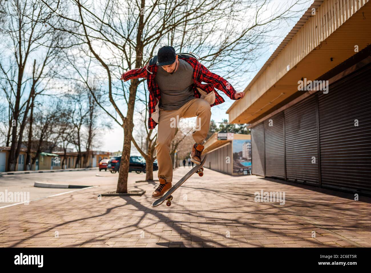 Ein junger Hipster-Mann macht einen Sprung mit einem Skateboard, Kickflip oder Ollie. Konzept des aktiven Lebensstils und der Straßenkultur. Stockfoto