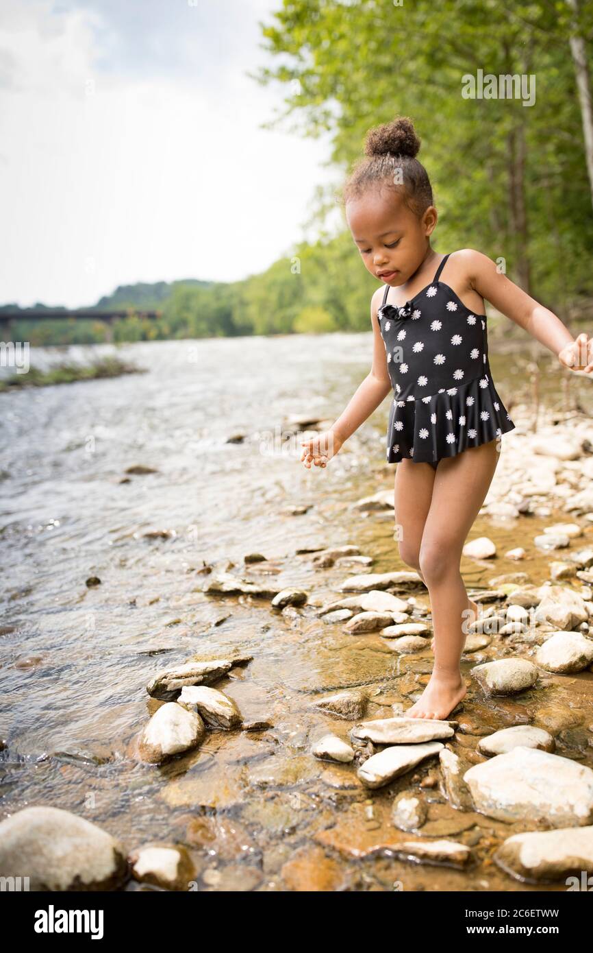 Ein junges Mädchen aus gemischter Rasse wadet im flachen Wasser des Shenandoah River bei Harpers Ferry, West Virginia, USA. Stockfoto