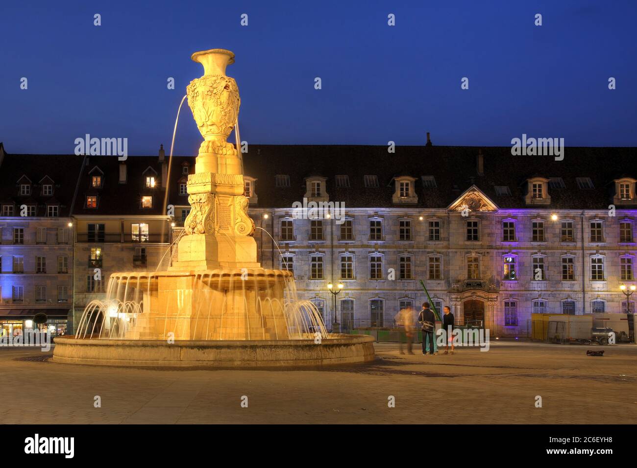 Ein Brunnen auf dem Platz der Revolution (Place de la Revolution) in Besancon, Frankreich bei Nacht mit dem städtischen Konservatorium im Hintergrund. Stockfoto