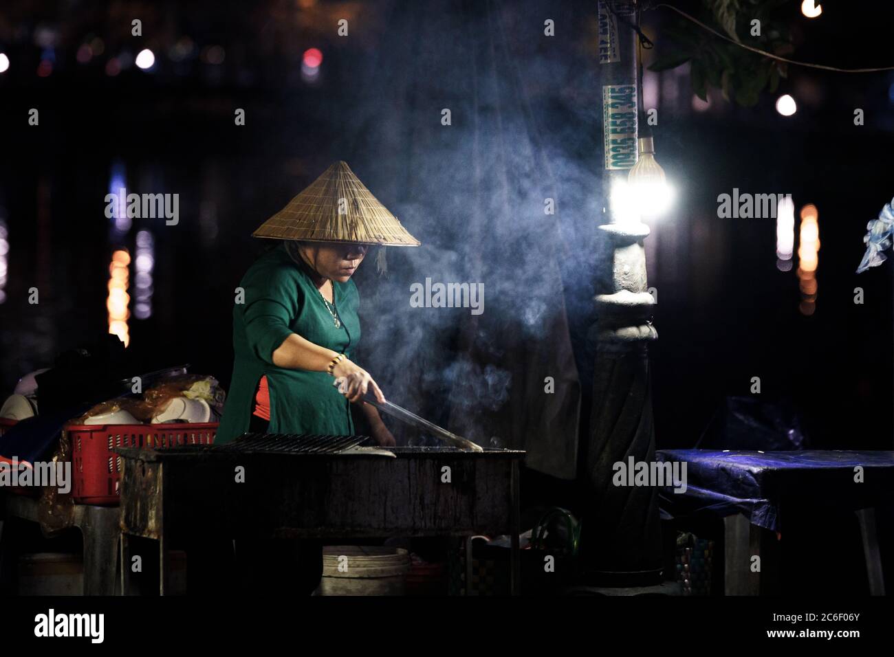 Frau mit vietnamesischem Hut Kochen auf einem Grill in der Nacht Stockfoto