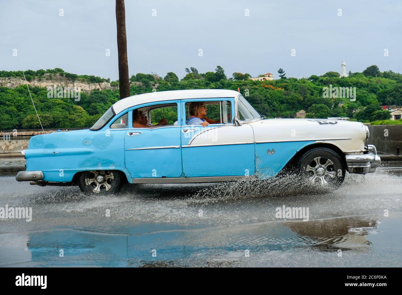 Ein klassischer Oldtimer fährt durch eine Pfütze in Habana Vieja in Havanna, Kuba. Stockfoto