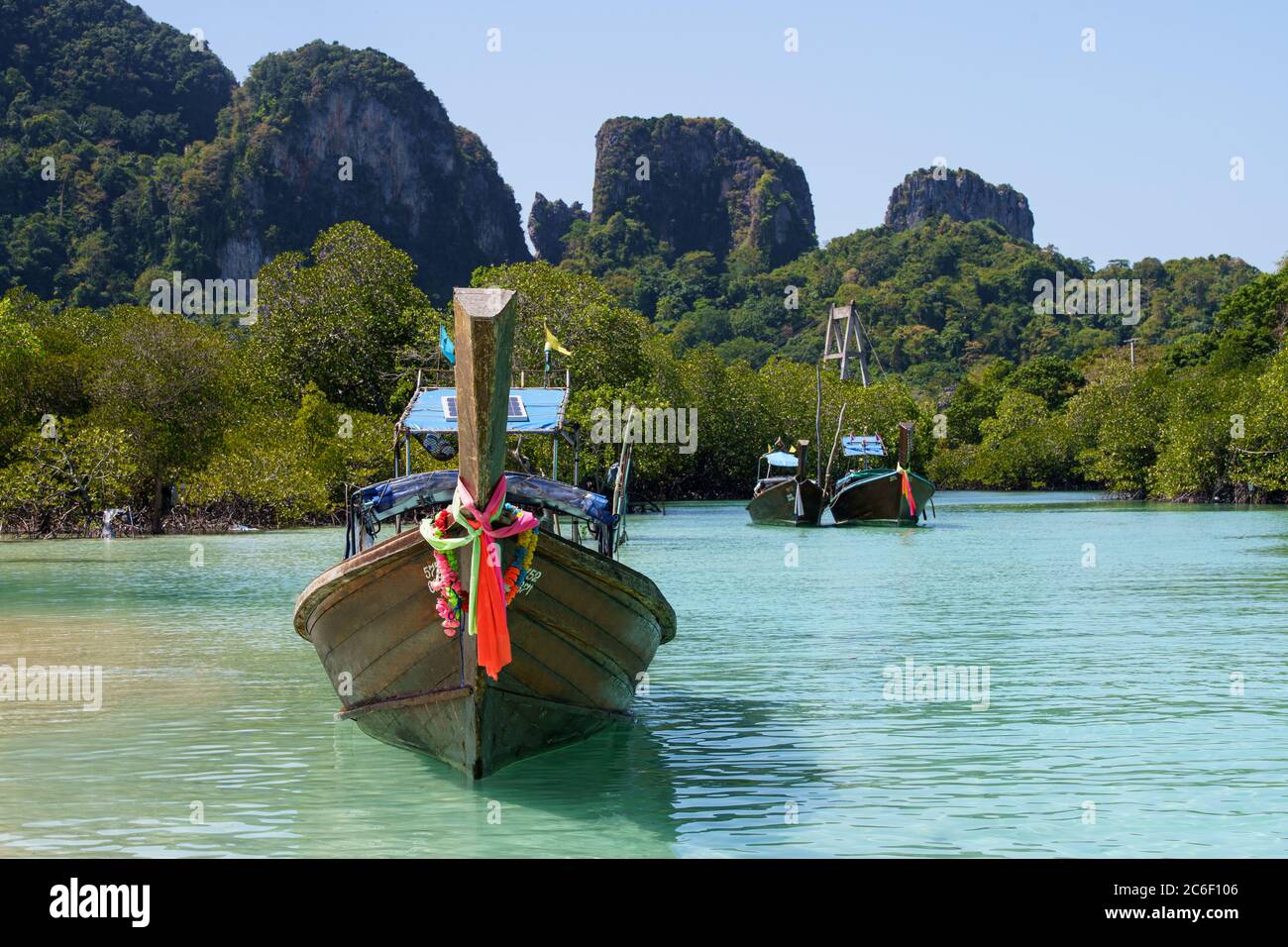 Asiatisches Boot auf türkisfarbenem Wasser mit anderen Booten dahinter Stockfoto